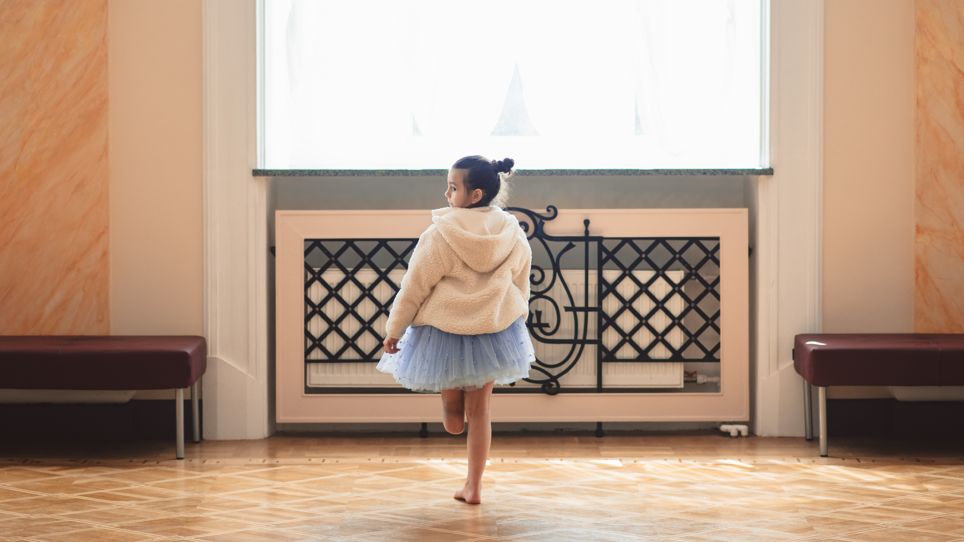 A child in a tutu walking toward the light